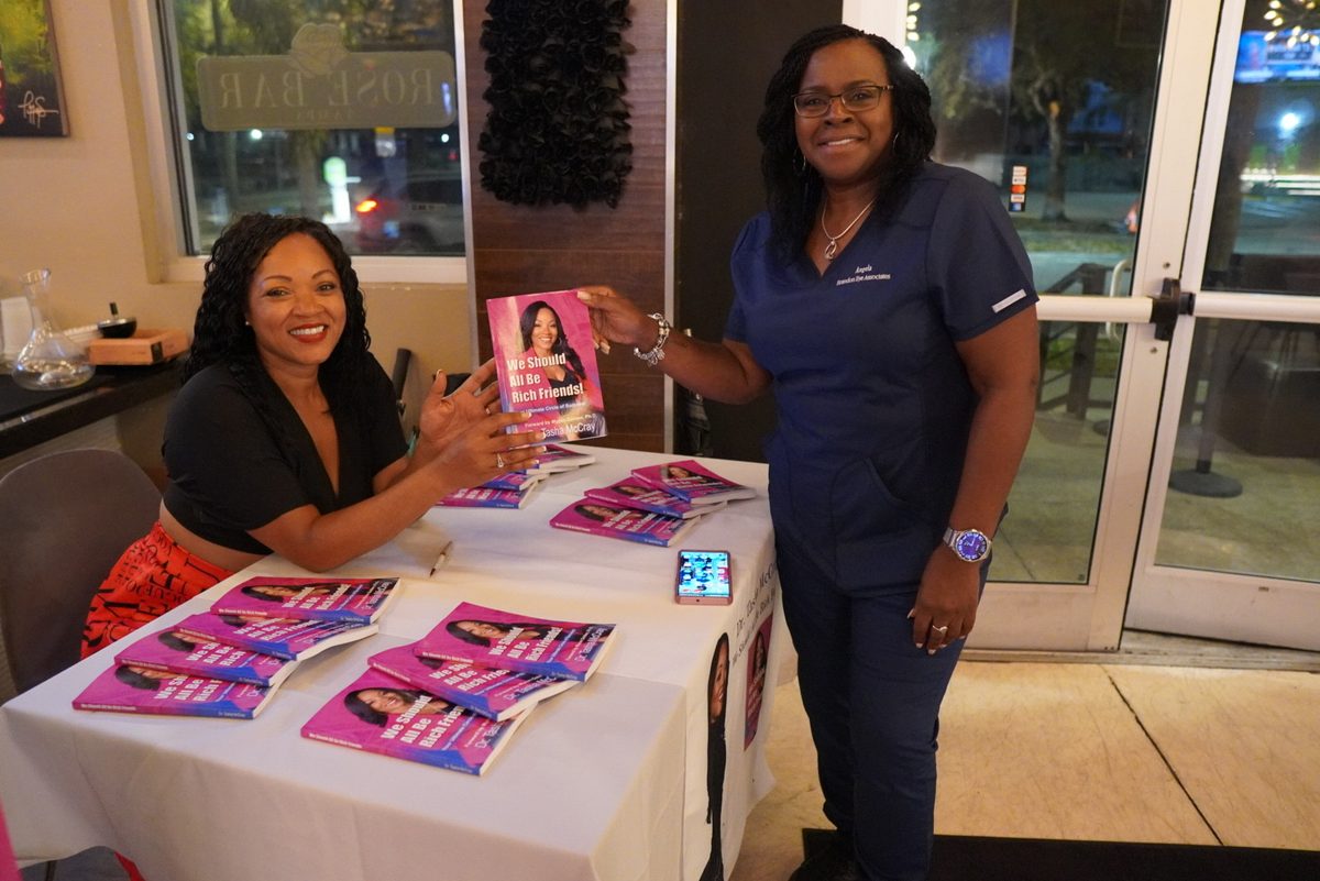Dr. TMac signing a copy for a reader in scrubs